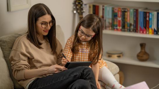 Child and adult together behind computer